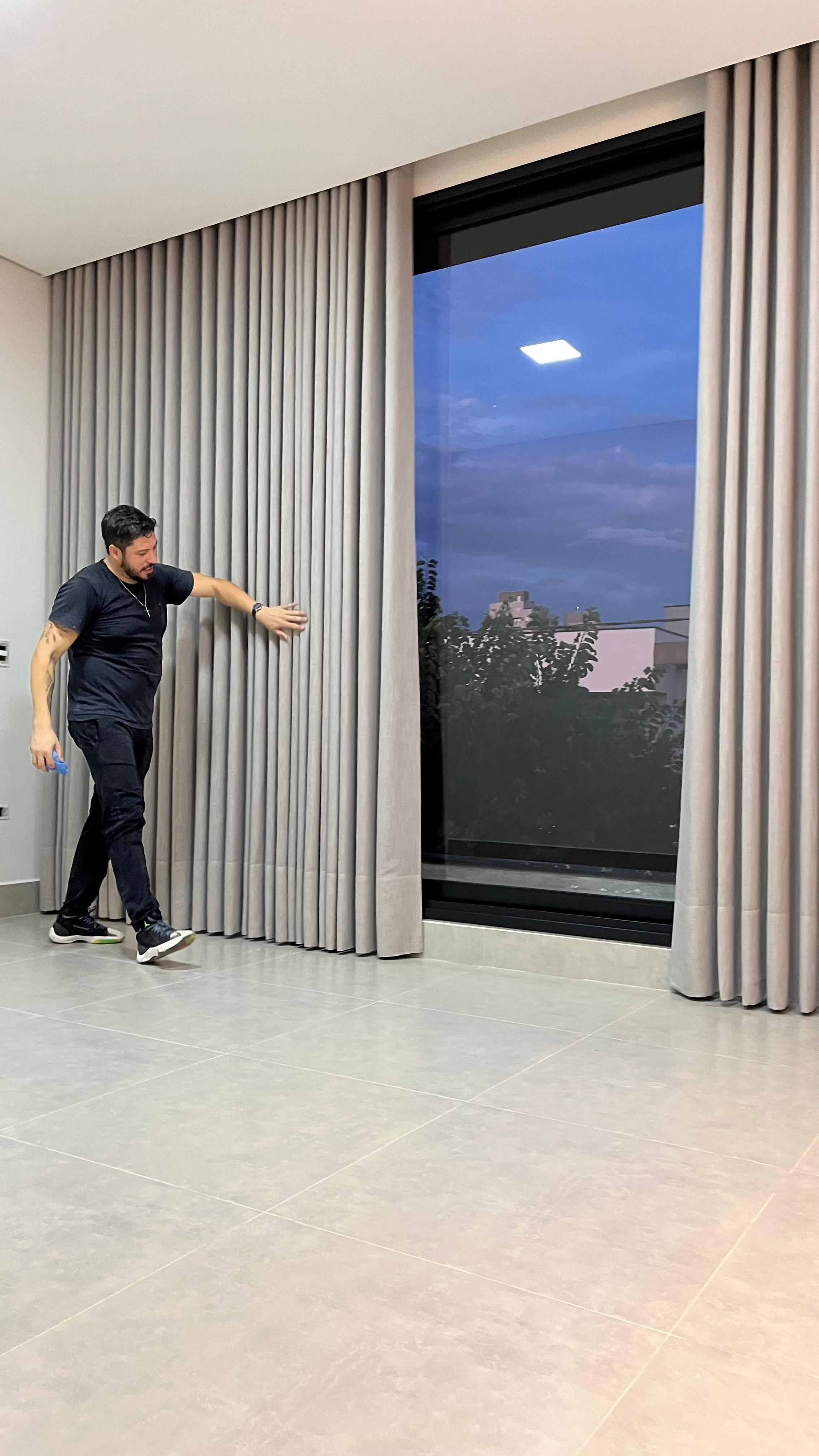 Instalador da SrHouse Decor ajustando cortina de voil ao entardecer